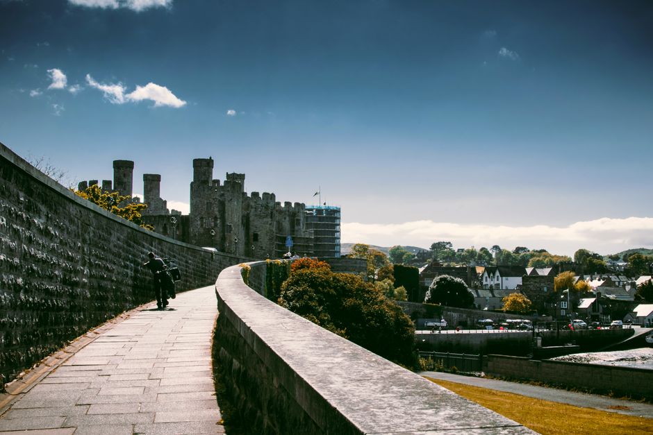 Explore the historic Conwy Castle and town walls under a bright, sunny sky in Conwy, Wales.