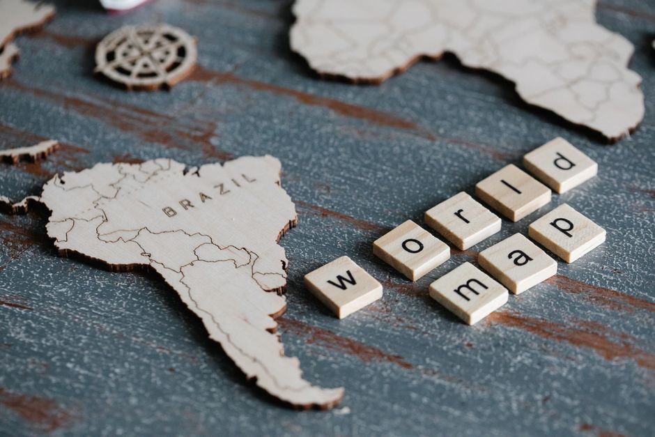 Wooden world map pieces with Scrabble tiles spelling 'world map' on textured background.